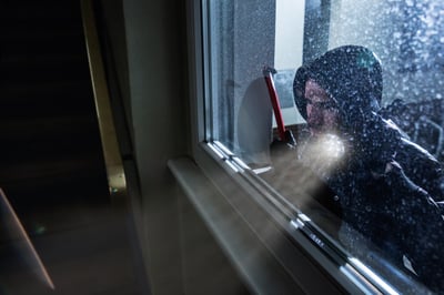 burglar looking through a window with a flashlight