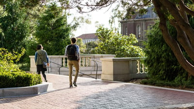 two people walking on a college campus near stairs