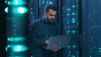 man holding a laptop in a data center